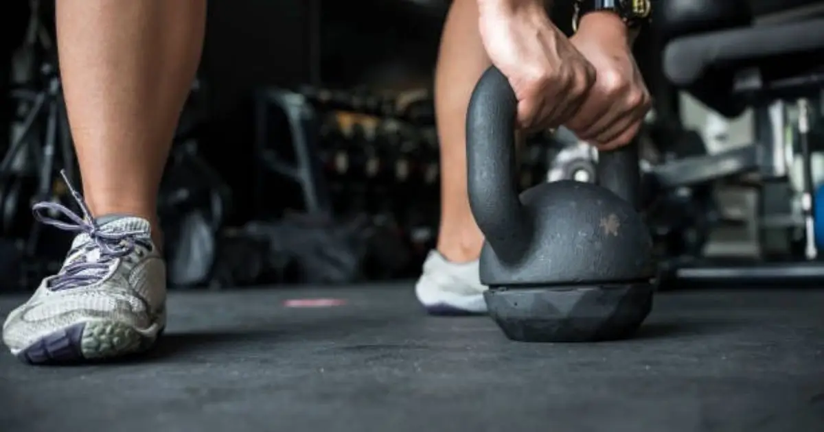 A close-up of a person gripping a kettlebell, preparing for an intense HIIT workout in the gym.