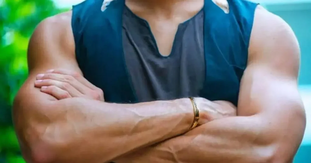 Person with muscular forearms crossed, showcasing the results of a calisthenics forearm workout.
